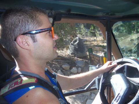 1968 Ford Bronco - A man navigates a rough trail in an off-road vehicle, with a trail marker visible.