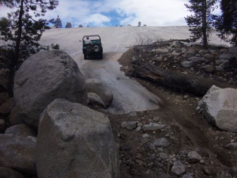 1968 Ford Bronco - A Jeep CJ-5 navigates a challenging snowy and rocky incline.