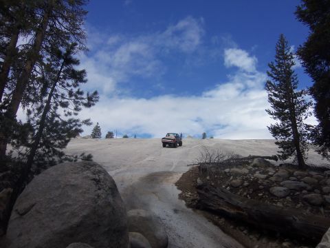 1968 Ford Bronco - Pickup truck navigates a snowy incline under a cloudy blue sky.