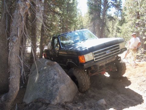 1968 Ford Bronco - Ford pickup truck is off-roading on a rocky, wooded trail.