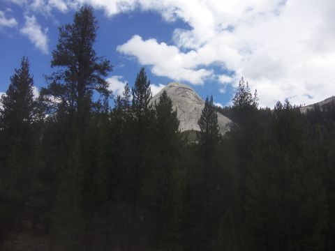 1968 Ford Bronco - A scenic view of a rocky mountain peak surrounded by dense evergreen trees on a partly cloudy day.