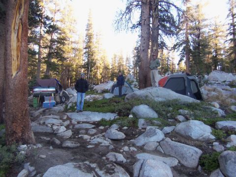 1968 Ford Bronco - A group of people are camping in a rocky, wooded area with tents set up.