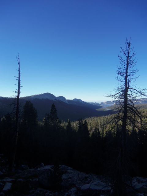 1968 Ford Bronco - A vast mountain vista unfolds under a deep blue sky, with silhouetted trees in the foreground.