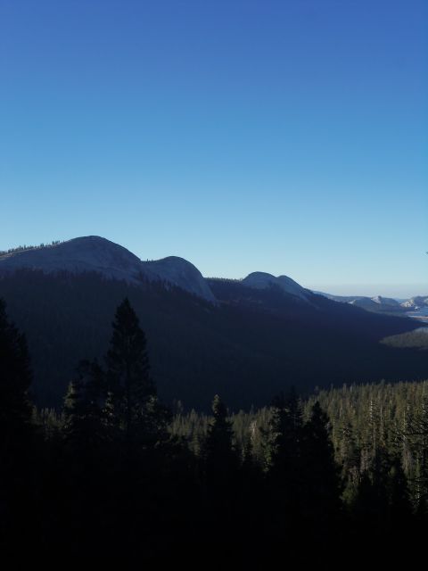 1968 Ford Bronco - A vast mountain landscape unfolds under a clear blue sky, with dense forests covering the slopes.