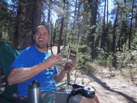 1968 Ford Bronco - A man sits in a camping chair in a forest, holding a small box.