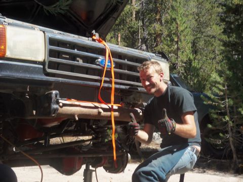 1968 Ford Bronco - Man working on truck suspension with another vehicle in the background.