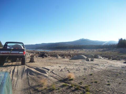 1968 Ford Bronco - A truck drives on a dusty trail with a mountain range in the background.