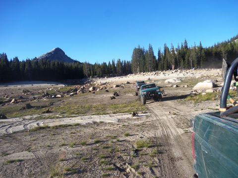 1968 Ford Bronco - Two off-road vehicles traverse a dry, rocky landscape under a clear blue sky.