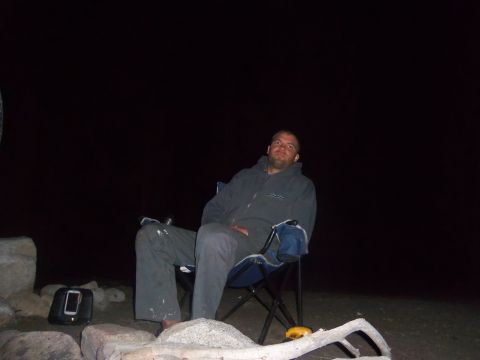 1968 Ford Bronco - A man is seated in a camping chair outdoors at night, with rocks and a cell phone visible in the foreground.
