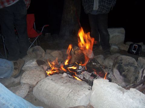 1968 Ford Bronco - People gathered around a campfire at night, with a red camping chair visible.