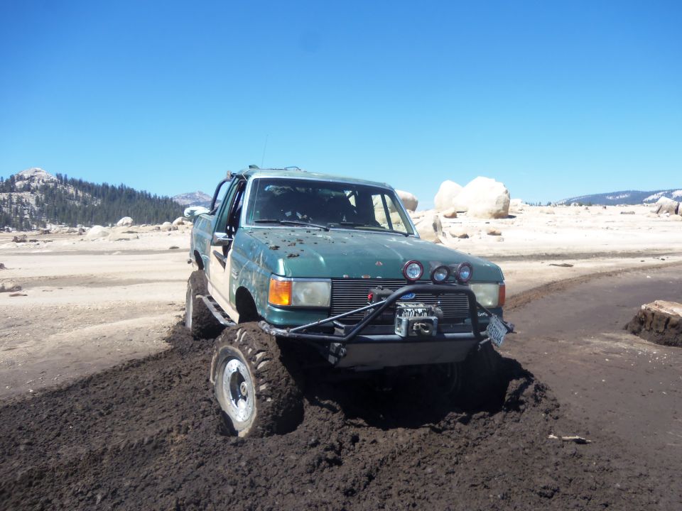 Green off-road truck stuck in mud with winch and spotlights