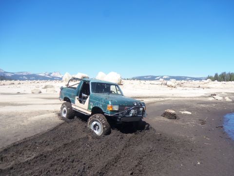 1968 Ford Bronco - This modified truck is stuck in thick mud on a dry lake bed under a clear blue sky.