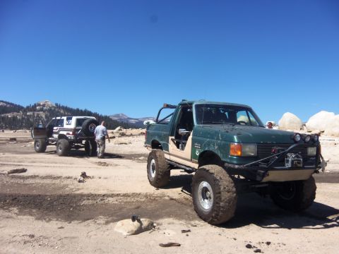 1968 Ford Bronco - Two off-road vehicles are seen in a dry, rocky landscape under a clear blue sky.
