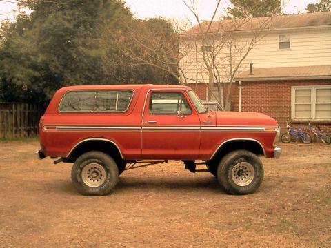 1978 Ford Bronco - This lifted 1978 Ford Bronco is parked in a dirt lot with a house in the background.