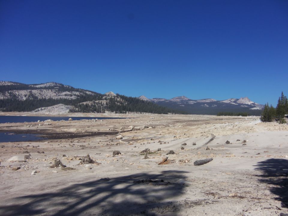 dry lake bed with mountains and trees under a clear blue sky. Supermotors logo in corner