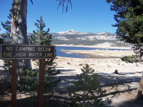 1968 Ford Bronco - A sign warns against camping below the high water line next to a lake with mountains in the background.