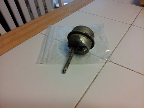 1976 Ford Ranchero - A metal vacuum actuator with a rod is shown on a tiled surface.