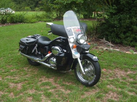 1998 Honda Shadow VT750C - A black 1998 Honda Shadow VT750C motorcycle is parked on a grassy lawn with trees in the background.