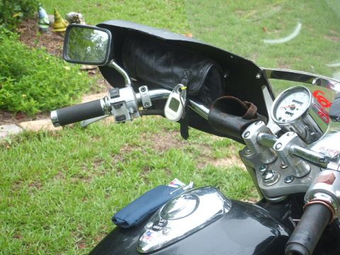 1998 Honda Shadow VT750C - Close-up view of motorcycle handlebars, a speedometer, mirror, and a leather pouch attached to the windshield.