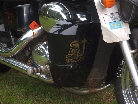1998 Honda Shadow VT750C - Close-up of a motorcycle's black side panel a 'Patriots Pray' decal and other stickers.