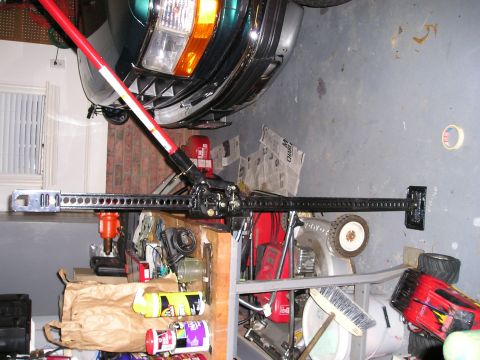 1996 Ford Bronco - A Hi-Lift Jack is positioned near the front of a green vehicle, with various tools and supplies in the background.