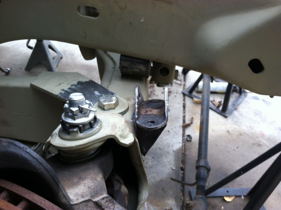 Close-up of vehicle suspension parts, including a ball joint and mounting bracket, with a Supermotors.net watermark