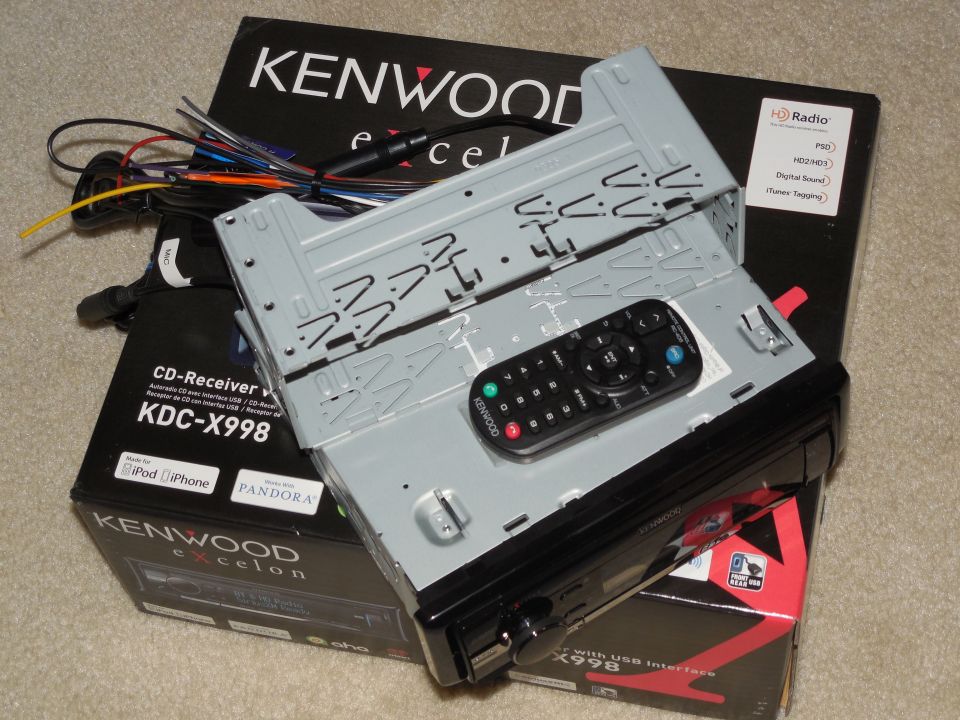 Kenwood Excelon KDC-X998 car stereo with mounting sleeve, wiring harness, and remote on its box