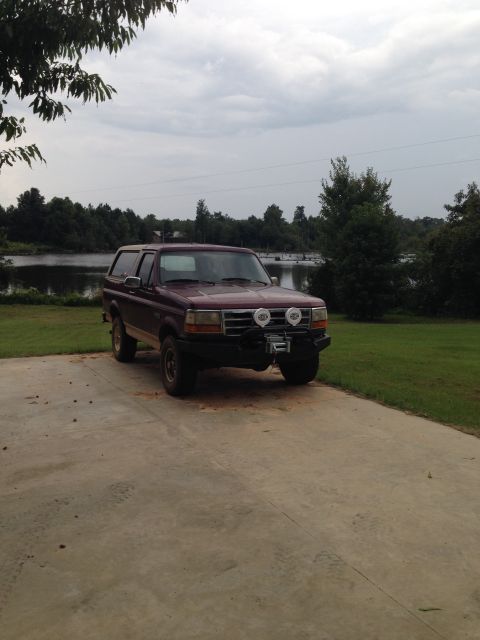 1996 Ford Bronco - This 1996 Ford Bronco features an aftermarket bumper and winch, parked outdoors near a body of water.