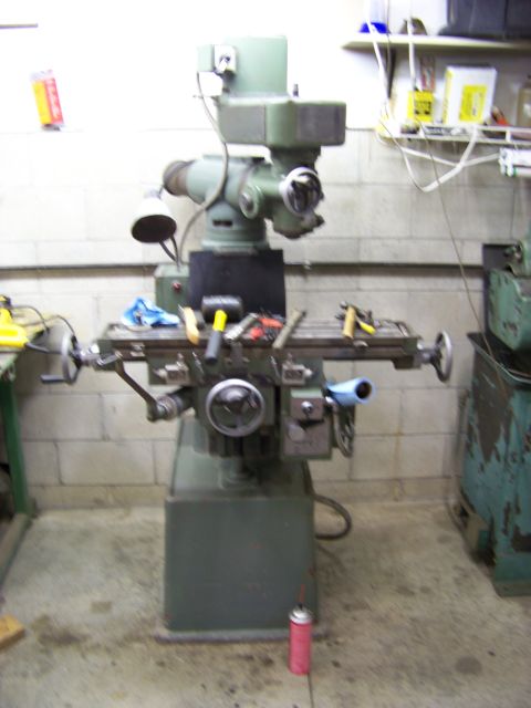 1974 Dodge Challenger - A milling machine sits in a workshop, with tools scattered on its work surface.