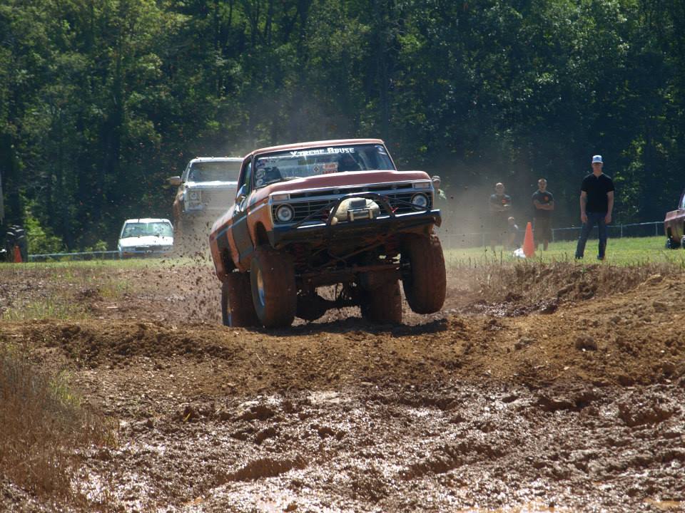 Orange pickup truck mid-air over mud, 1977 grille
