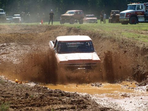 1978 Ford Bronco - A pickup truck navigates a muddy obstacle course, sending up a large spray of mud.