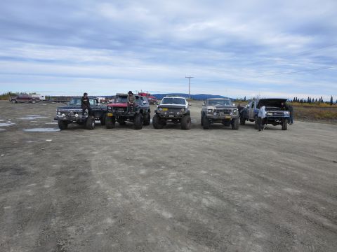 1990 Ford F-250 - A group of modified Ford trucks are gathered outdoors on a dirt surface.