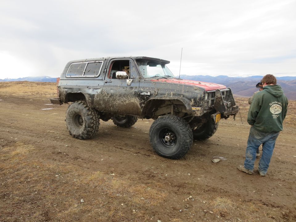 Muddy SUV with large tires and red hood
