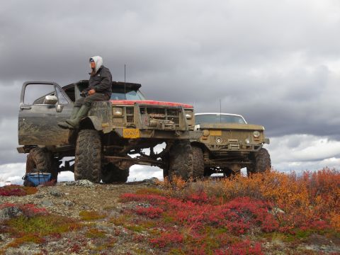 1990 Ford F-250 - Two custom off-road trucks are parked on a hillside with colorful autumn brush.