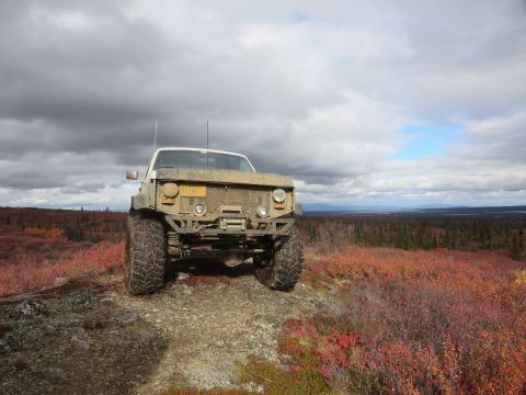1990 Ford F-250 - A heavily modified pickup truck sits on a rocky incline overlooking a vast, autumnal landscape under a cloudy sky.