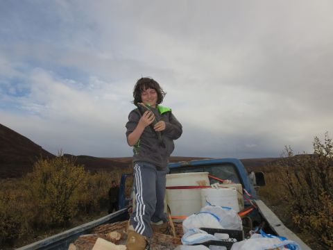 1990 Ford F-250 - A child proudly displays a fish while standing in the bed of a pickup truck loaded with supplies.