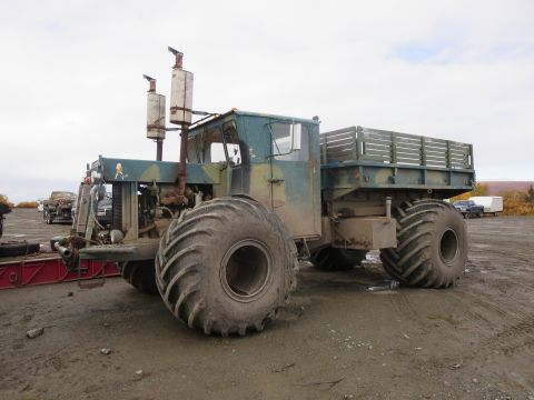 1990 Ford F-250 - This heavy-duty truck features oversized tires and a flatbed with wooden sides, suggesting it's built for rough terrain.