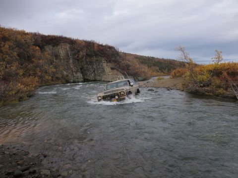 1990 Ford F-250 - This Ford F-Series truck is navigating a river during autumn, with trees showing fall colors on the banks.