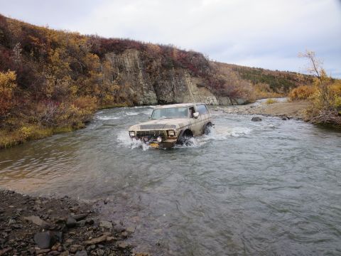 1990 Ford F-250 - A 1978 Ford Bronco navigates a shallow river during autumn.