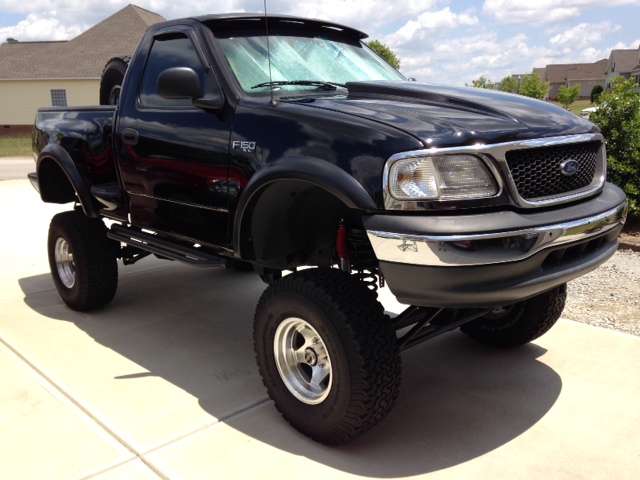 Lifted black pickup truck with custom hood and large tires
