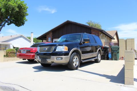 2003 Ford Expedition - A black Ford Expedition is parked in a driveway on a sunny day, with a red sedan beside it.