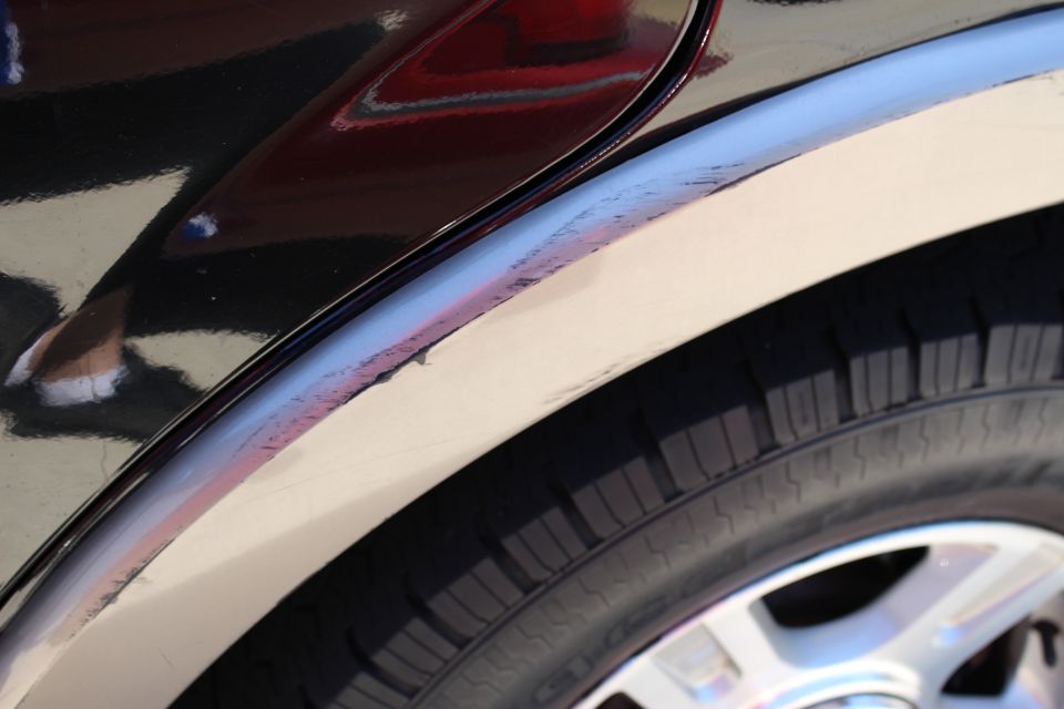 Close-up of a vehicle's rear fender and tire. The fender has some scuffs and scratches