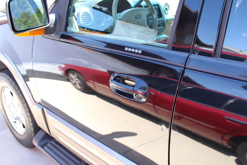 Black SUV side door with keypad entry and reflection of red car