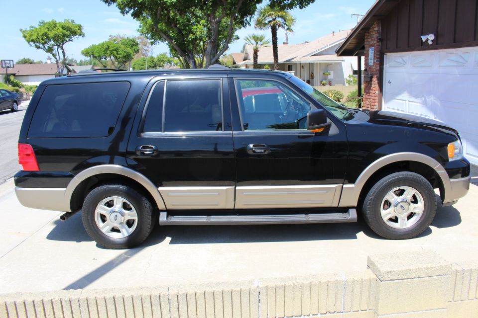 Side view of a black 2003 Ford Expedition with tan lower body trim parked on a sunny day