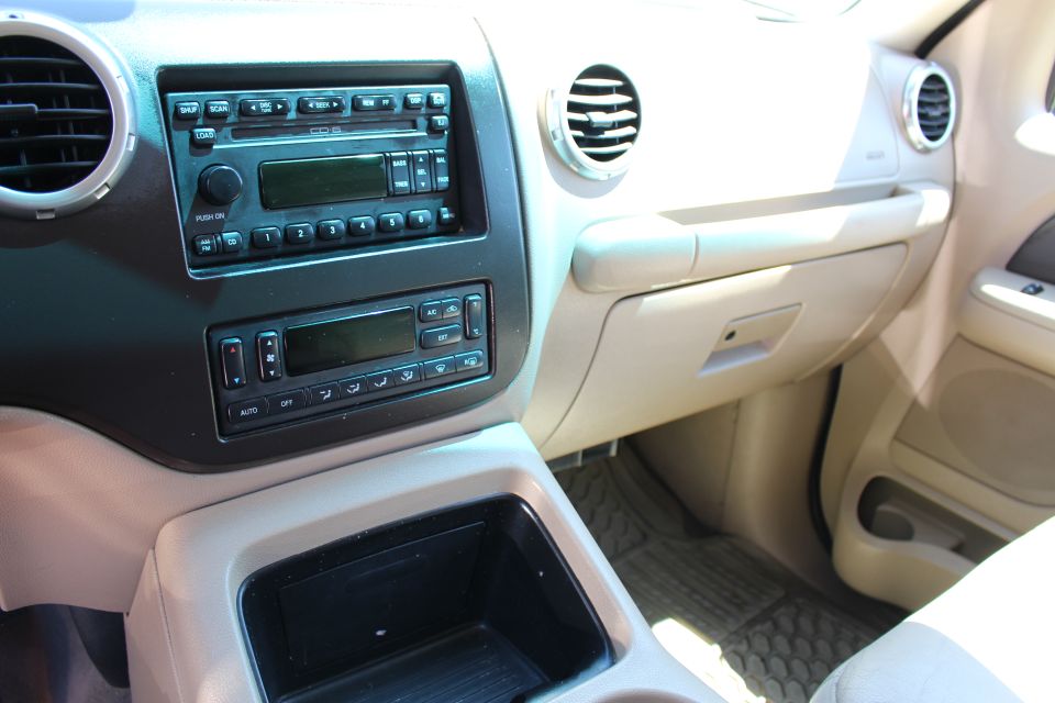 Tan car interior showing dashboard with radio, climate controls, and glove compartment. Visible text includes 'AUTO' and 'OFF'