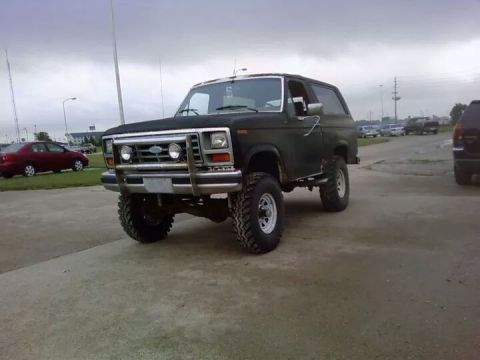 1986 Ford Bronco - This lifted SUV features a prominent chrome grille and brush guard, suggesting an earlier model year.