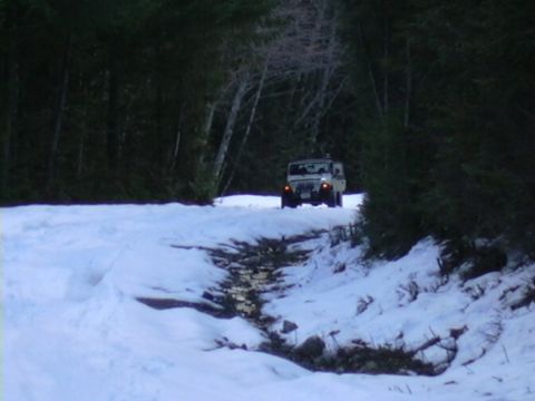 1991 Ford Bronco - A Jeep Wrangler navigates a snowy path in a wooded area during winter.