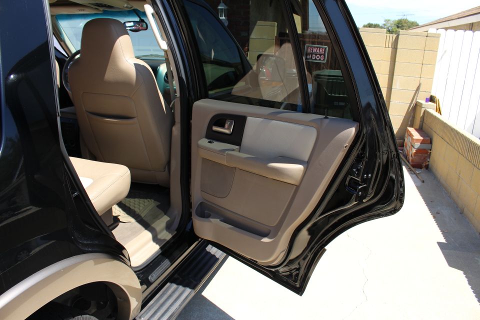 Interior shot of a black SUV, showing the driver's seat, passenger seat, and door panel. A 'Beware of Dog' sign is visible on the rear door
