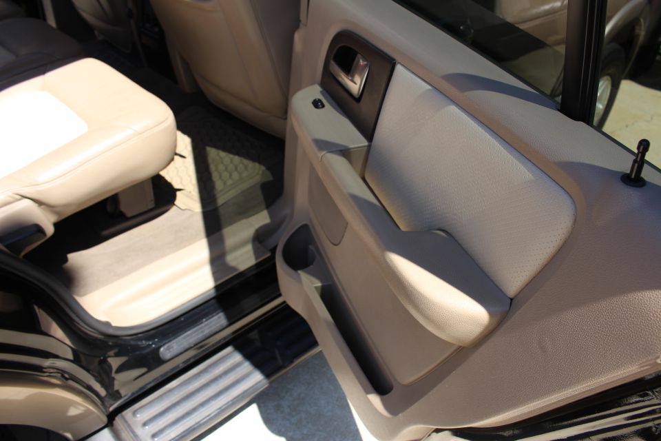 Tan leather seats and door panel inside a vehicle with the door open