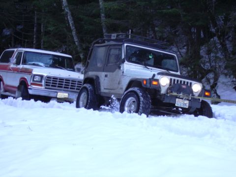 1991 Ford Bronco - A white and red Ford Bronco is stuck in deep snow next to a Jeep Wrangler during a winter outing.